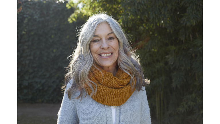 Portrait of woman with long gray hair looking at camera smiling