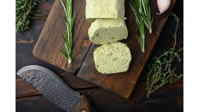 Homemade Butter with thyme and rosemary and lemon zest, on old dark  wooden table background