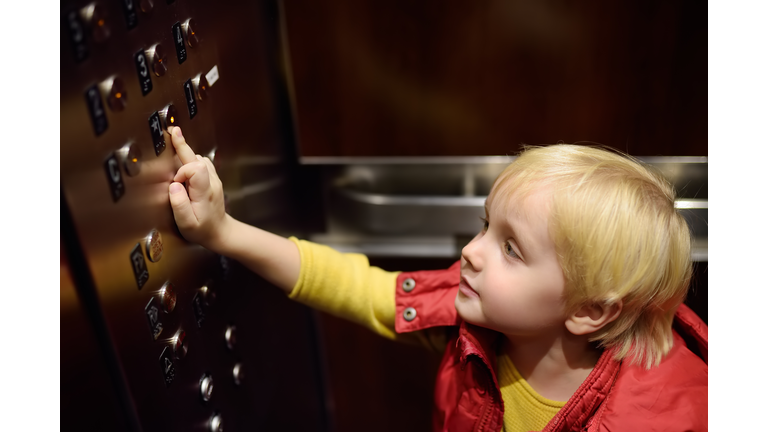 Lttle boy pressing button of lobby in elevator