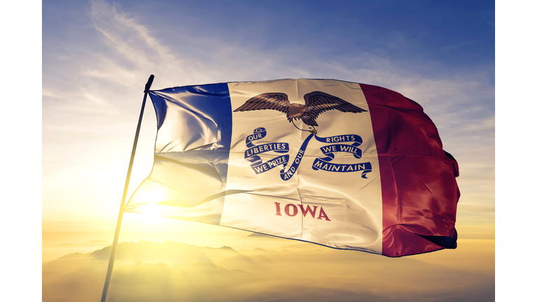 Iowa state of United States flag textile cloth fabric waving on the top sunrise mist fog