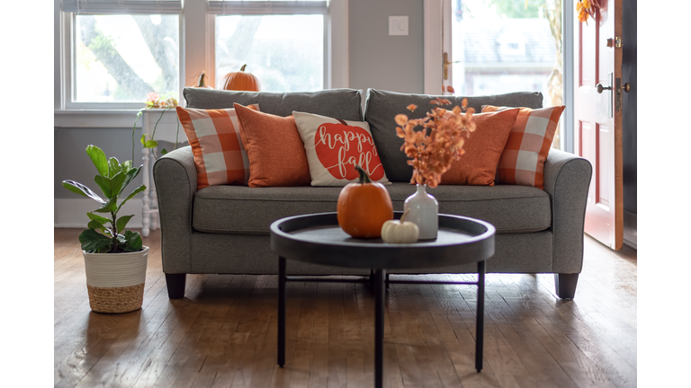 Home interior decorated for fall with orange accent pillows on the sofa