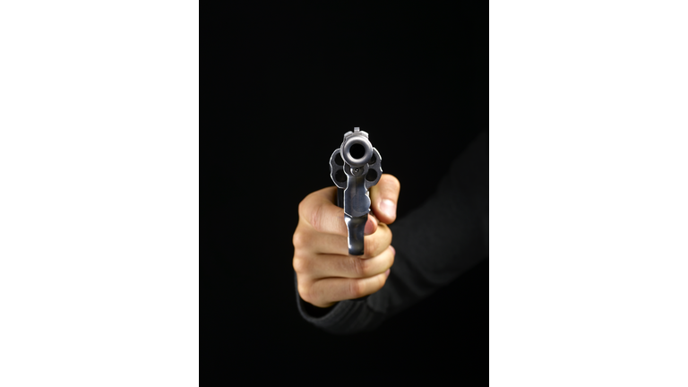 Gun pointing at camera on black background.