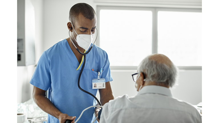 Nurse examining patient in clinic during COVID-19