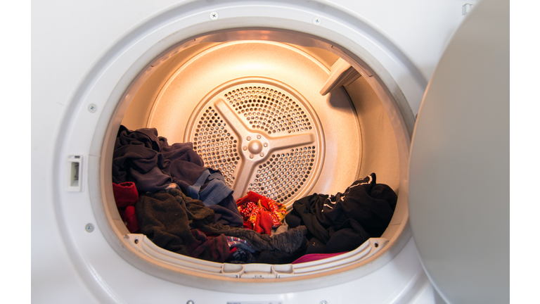 Front view of open clothes drier with laundry inside