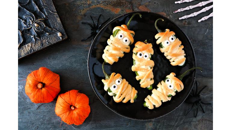 Halloween mummy jalapeno poppers, scene on dark stone