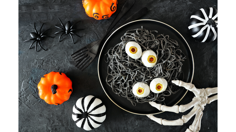 Halloween eyeball spaghetti table scene over a dark background with orange, black and white decor