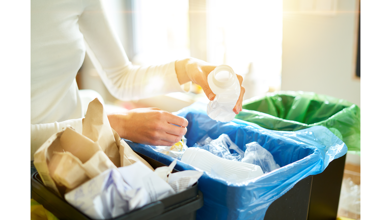 Young woman sorting garbage in kitchen.