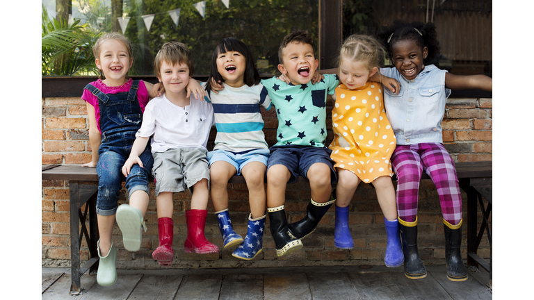 Kindergarten kids friends arm around sitting smiling