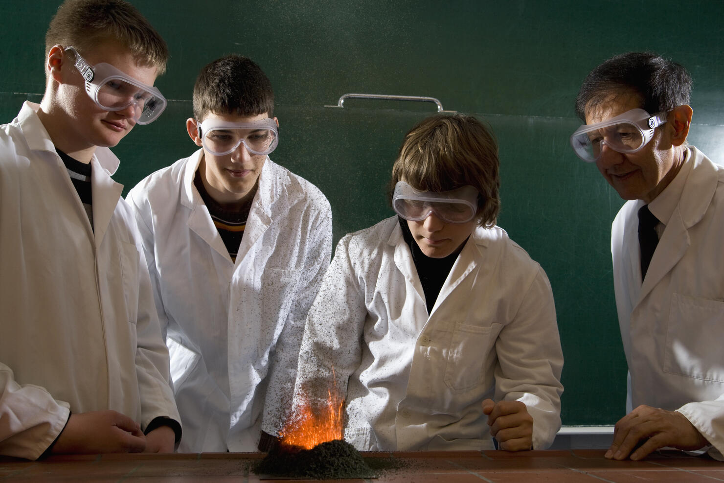 A teacher supervising students doing a chemistry experiment with lit gunpowder