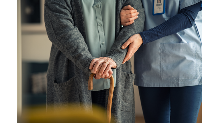 Nurse assisting senior with walking cane