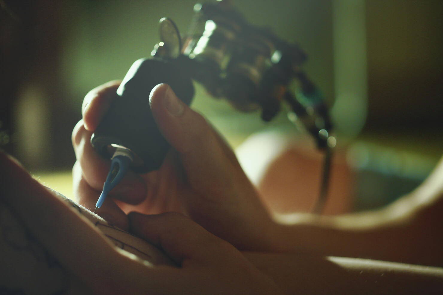 Tattoo master tattooing on the a girl arm.