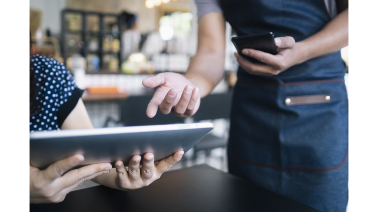 Young waiter using a digital tablet to show the menu to a customer.