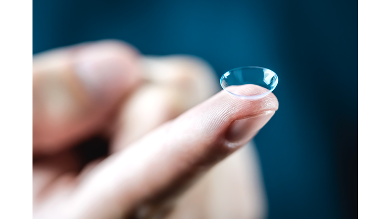 Contact lenses macro close up. Man holding lens on finger. Customer, patient or eye doctor, oculist or optician in clinic.