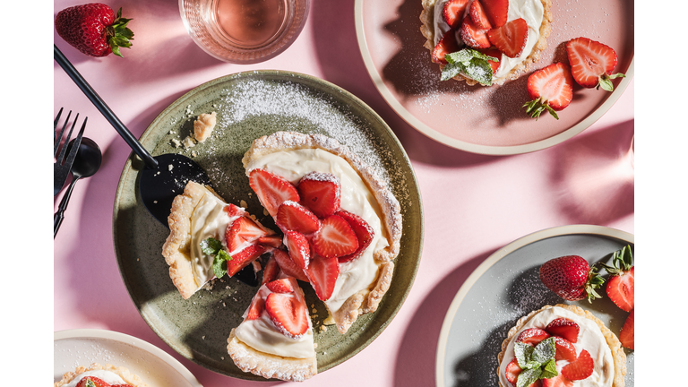 Summer sweet strawberry tarts on pink background with harsh shadows