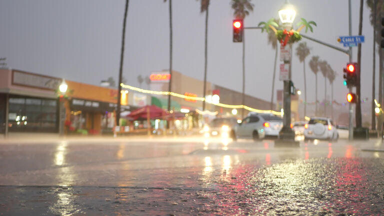 Lights reflection on road in rainy weather. Palm trees and rainfall, California.