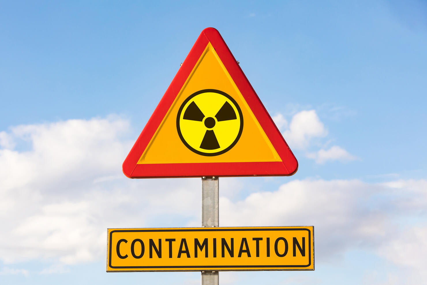 Danger traffic sign with the nuclear symbol and sign that says: 'CONTAMINATION', with the sky in the background. Concept of war, Ukraine, Russia and war conflict. Concept of energy and chemical weapon,.