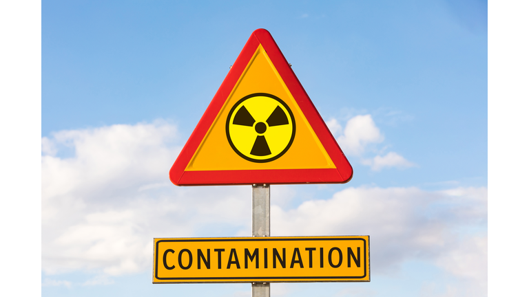 Danger traffic sign with the nuclear symbol and sign that says: 'CONTAMINATION', with the sky in the background. Concept of war, Ukraine, Russia and war conflict. Concept of energy and chemical weapon,.