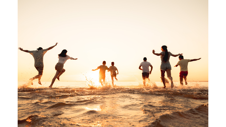 Big group of friends or big family run at sunset beach