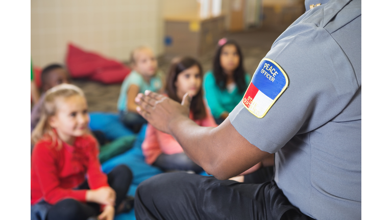 Closeup of police officer talking to young class on campus