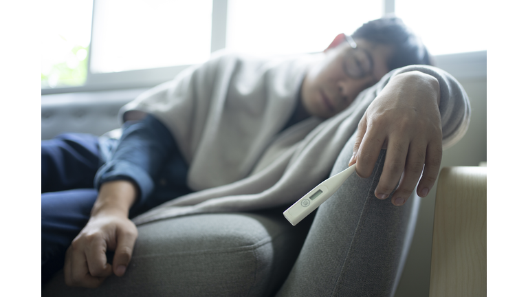 asian young man feeling sick and  very exhausted and sleeping on sofa at home