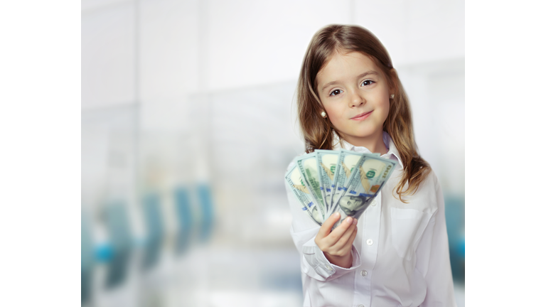 Child girl holding money in hands financial background.