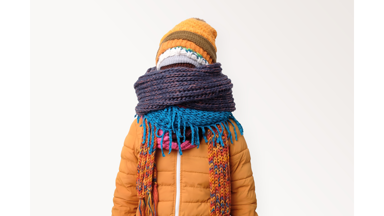 Handsome caucasian funny man hiding face in several hats and scarfs.