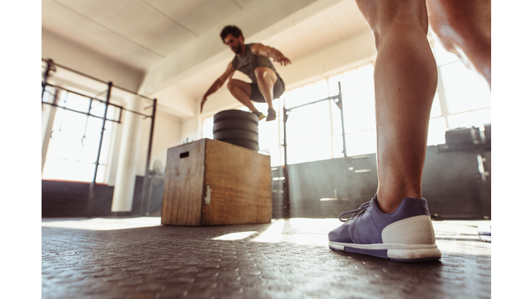 Fit man box jumping at cross training gym