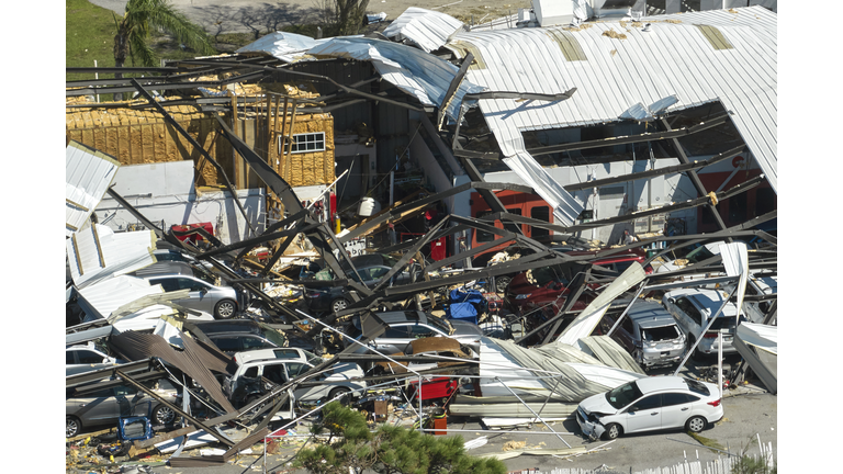Hurricane Ian destroyed industrial building with damaged cars under ruins in Florida. Natural disaster and its consequences
