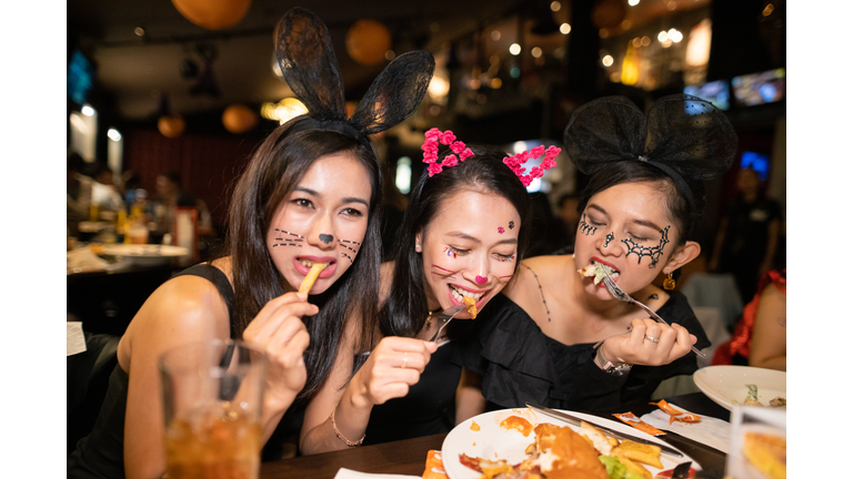 Asian women in halloween costume eating dinner at restaurant together