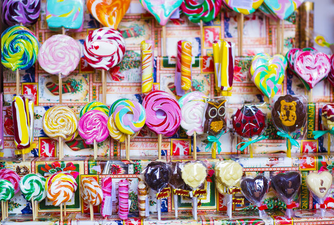 Great choice of colorful caramel on stick and chocolate candy for sale in shop window