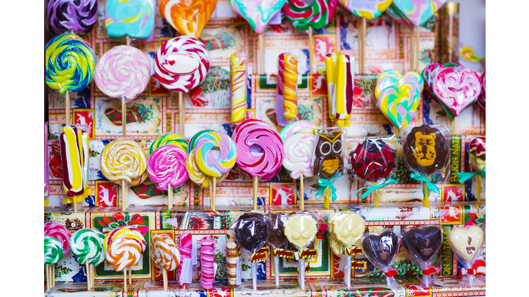 Great choice of colorful caramel on stick and chocolate candy for sale in shop window