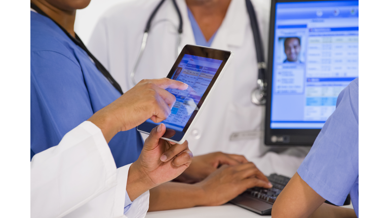 Doctors using digital tablet together in hospital