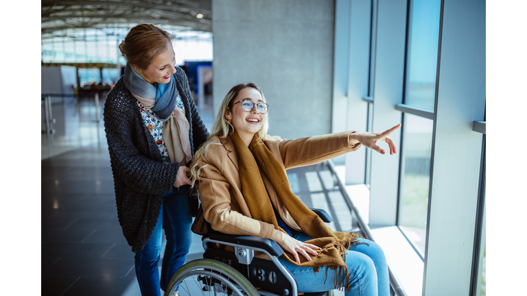 Young disabled woman on wheelchair and mother waiting at airport