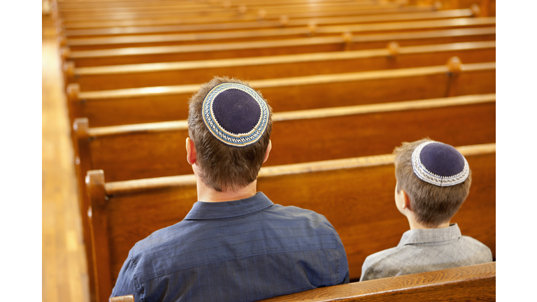 Father and son in yarmulkes sitting in synagogue