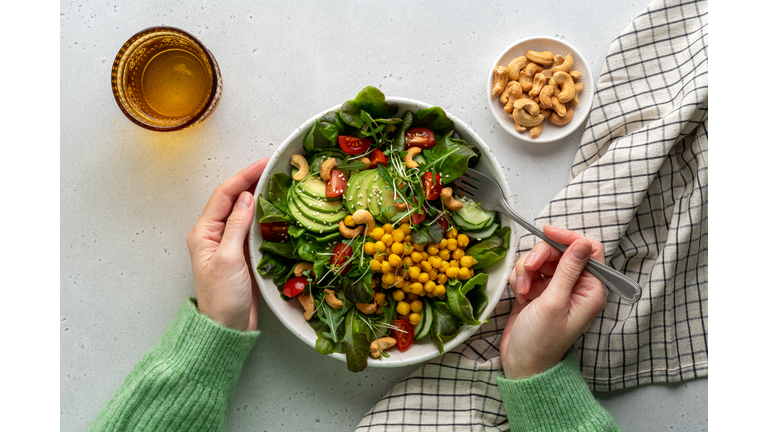 Faceless female eating healthy vegan plant-based salad in bowl with fatty acids and dietary fiber