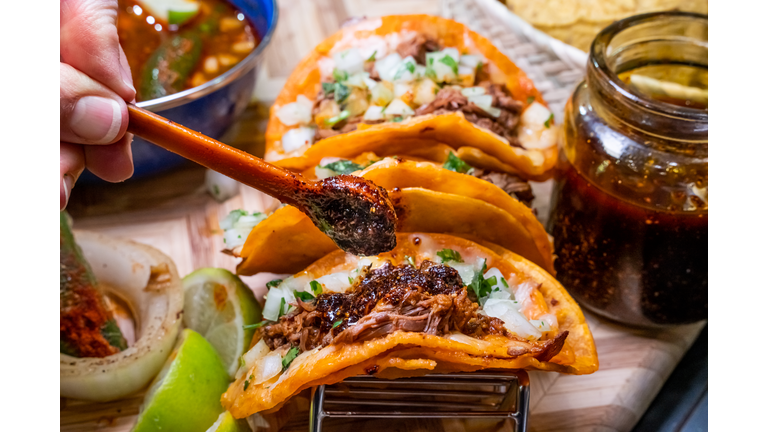 Authentic Gourmet Birria Tacos And A Bowl Of Delicious Mexican Consume, Soup, Arranged On A Wood Cutting Board