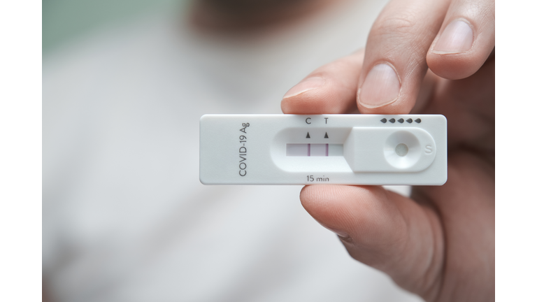 Close-up of a hand holding a positive antigen test for COVID-19.