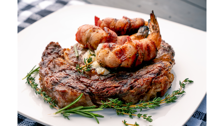 Char-Grilled Ribeye Steak with Thyme and Rosemary with Bacon-Wrapped Jumbo Shrimp or Prawns on a Plate, Ready to Eat