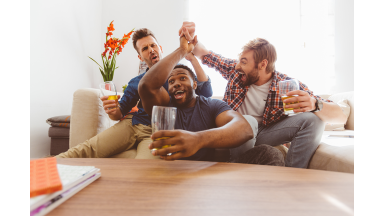 Three excited guys watching sport on tv