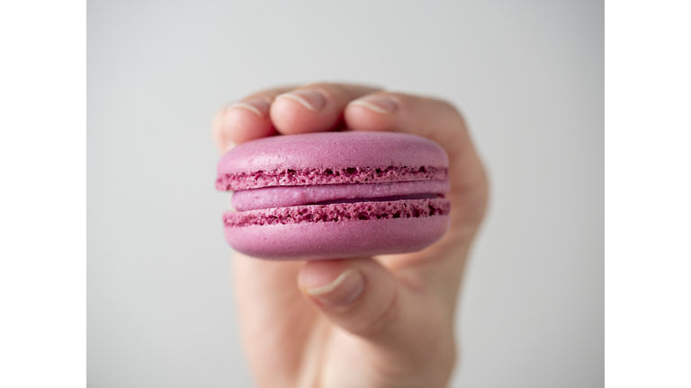 Purple sweet macaroon cookies in hand on a white background. Close-up, air-conditioning product