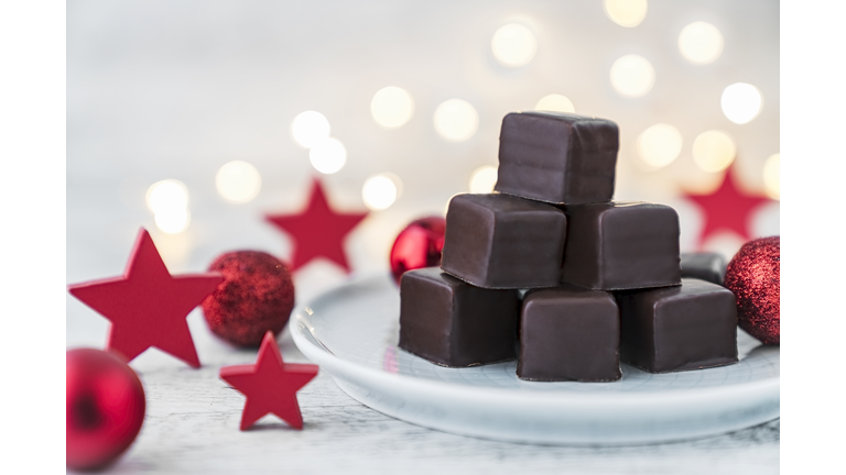 Dominosteine (chocolate pralines) on a plate with Christmas decoration.