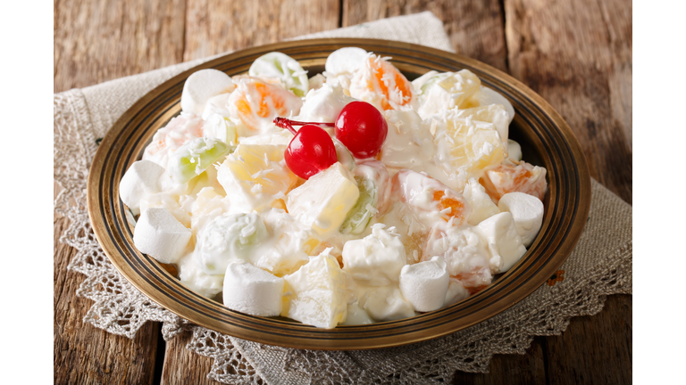fruit salad from pineapple, oranges, grapes and coconut with marshmallow and vanilla yogurt close-up. horizontal