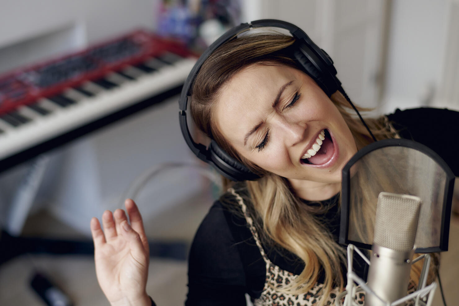 Young woman singing in home recording studio