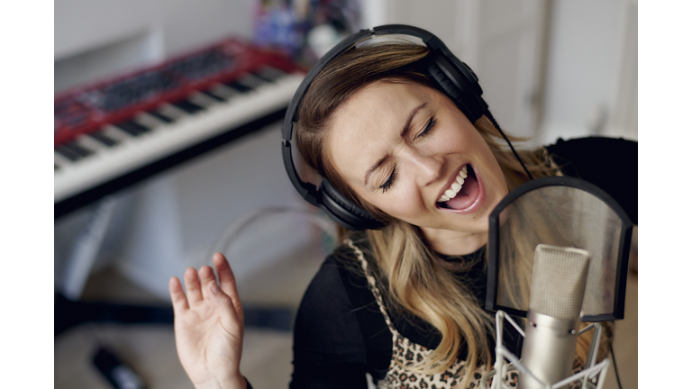 Young woman singing in home recording studio