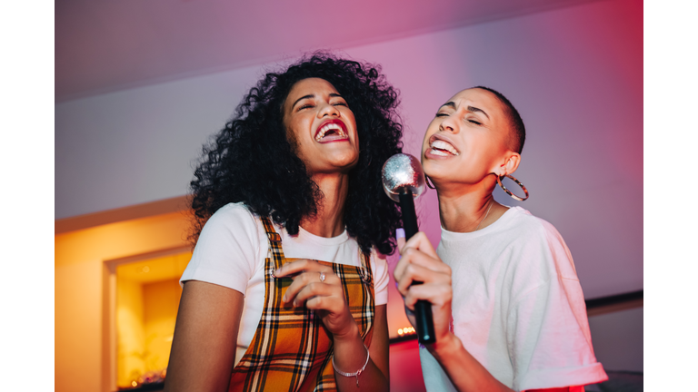 Best friends singing into a microphone on karaoke night