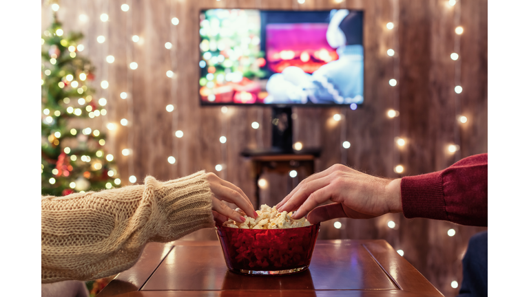 Christmas eve. Couple watching tv and eating popcorn. Home cinema. Cropped, close up