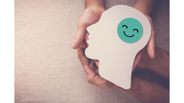 Adult and child hands holding smile face in brain paper cutout, happy hormones, brain chemicals, positive mental health concept