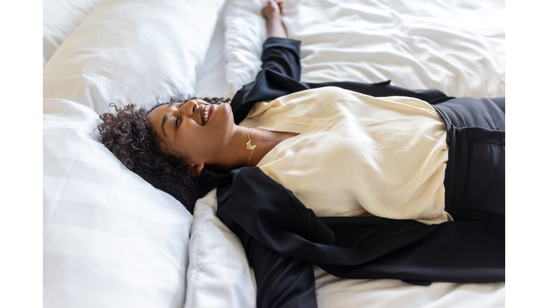 Exhausted businesswoman lying on hotel room bed