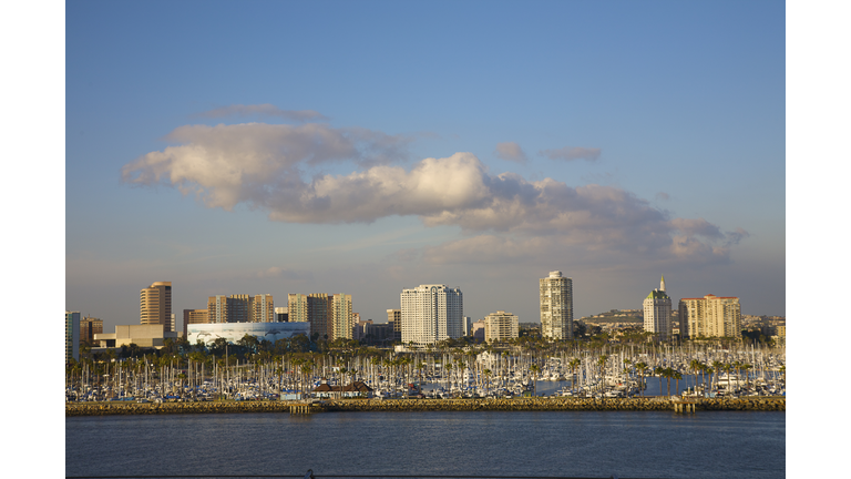 Long Beach, California, cloud formations in sky above modern city skyline and boat-filled marina
