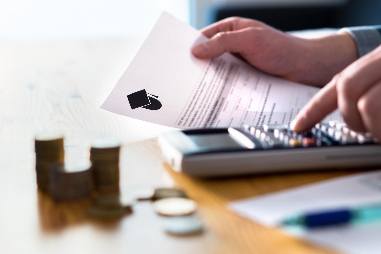 Man counting college savings fund, tuition fee or student loan with calculator. Education price and expenses concept. Money and papers on table.